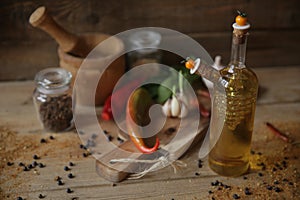 Olive oil in a bottle on a wooden background with a wooden board with spice and herbs for decoration
