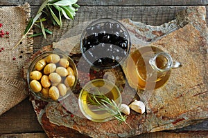 Olive oil in a bowl and carafe on vintage wooden boards.