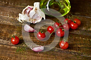 Olive oil, cherry tomatoes and garlic on a wooden table