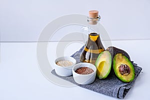 Olive oil in glass bottle with sesame and flax seeds. Fresh ripe hass avocado. Healthy eating. Vegetarian ingredients. Vegan diet