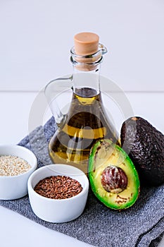 Olive oil in glass bottle with sesame and flax seeds. Fresh ripe hass avocado. Healthy eating. Vegetarian ingredients. Vegan diet