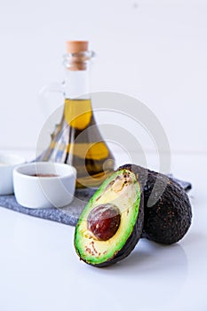 Olive oil in glass bottle with sesame and flax seeds. Fresh ripe hass avocado. Healthy eating. Vegetarian ingredients. Vegan diet
