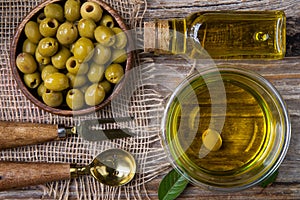 Olive oil in a glass bowl. olives in a wooden cup