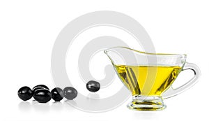 Olive oil in a gravy boat and black olives isolated on white background