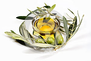 Olive oil. Greek olive oil in glass transparent bowl with olive branches with leaves and olives. Close-up on white surface