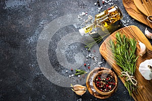 Olive oil, herbs and spices on a dark stone table.