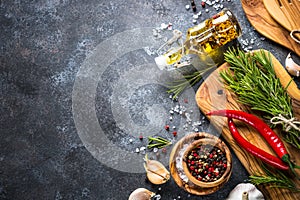 Olive oil, herbs and spices on a dark stone table.