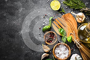 Olive oil, herbs and spices on a dark stone table.