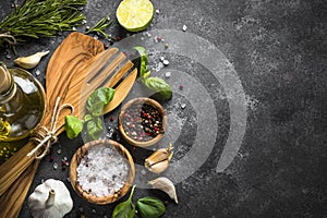 Olive oil, herbs and spices on a dark stone table.