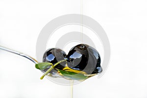 Olive oil over two olives branch in a spoon