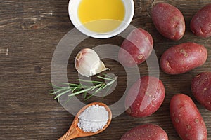 Olive oil porcelain plate Rosemary branch Pepper mix Garlic Seasoning Spices Raw potato Cooking concept Wooden background