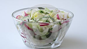 Olive oil is poured into a fresh salad of cabbage radishes cucumbers and onions