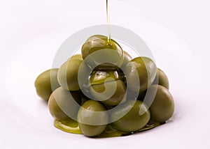 Olive oil is poured on olives on a white background. The concept of olive oil.