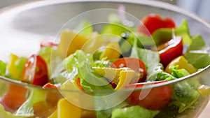 Olive oil pouring into bawl with vegetable salad