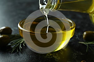 Olive oil pouring from bottle to bowl, close up