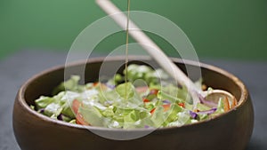 Olive oil pouring over mixed salad