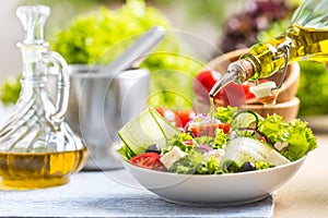 Olive oil pouring in to the fresh vegetable salad. Healthy mediterranean italian or greek cuisine