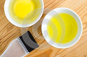 Olive oil and raw egg in a small ceramic bowls for preparing homemade spa face and hair masks. Ingredients for diy cosmetics.