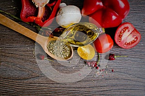 Olive oil, tomatoes and herbs on wooden table