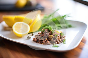 olive tapenade on a ceramic plate with lemon wedge