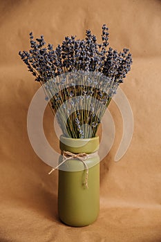 Olive vase with bouquet of lavender on kraft paper background