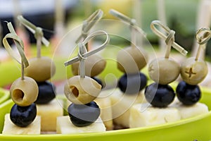 Olives and black olives with cheese on skewers. Festive serving in portions. Close-up