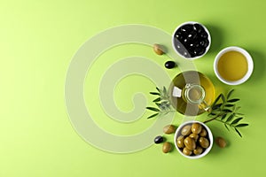 Olives, bottle and bowl with olive oil on green background
