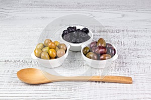 Olives in bowls and a wooden spoon.