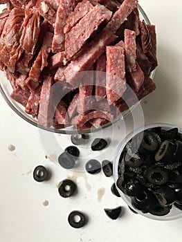 Olives, cut into rings and sausage, cut into strips. They lie in different containers.