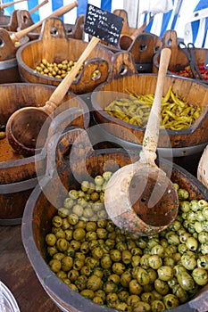 Olives and hot peppers in wooden vats at the market