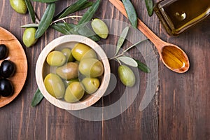 Olives, oilive oil and brunches on the wooden table, photo