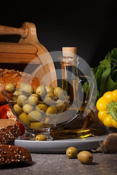 Olives, olive oil, vegetables and bread on a dark background
