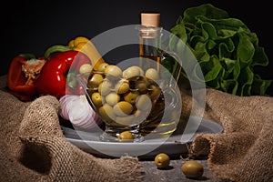 Olives, olive oil and vegetables on a dark background