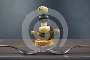 Olives, pickled cucumber, bread, mushrooms on a fork close-up on a dark background. food and vegetables. diet and weight loss