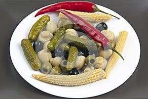 Olives, pickled cucumber, pepper, mushrooms and corn in a salad on a plate. food and vegetables. diet and weight loss