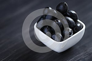 Olives in a white bowl on a dark wooden table