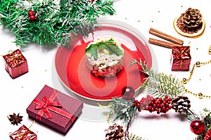 Olivier salad on a red plate . Olivier Christmas . Christmas layout with salad. New Year. Holiday. Festive dish. Table decoration