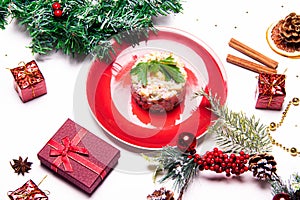 Olivier salad on a red plate . Olivier Christmas . Christmas layout with salad. New Year. Holiday. Festive dish. Table decoration