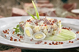 Olivier Salad or Russian Salat with Salmon and Red Caviar on Retro Ceramic Plate