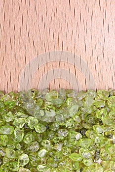 Olivine heap jewel on half light varnished wood texture. Pile mineral pebbles background