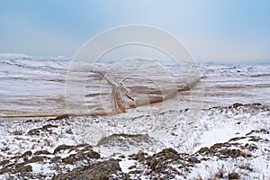 Olkhon island winter landscape. View of the mountains, frozen Lake Baikal and the federal highway Irkutsk-Khuzhir on a cloudy day