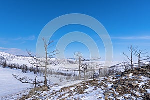 Olkhon island winter landscape. View of the mountains, frozen Lake Baikal and the federal highway Irkutsk-Khuzhir on a cloudy day