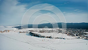 Olkhon, Khuzhir, Baikal. Panorama of the island from a drone. The snow-covered desert. Winter village in the background