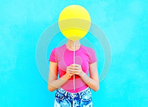 Ð¡olorful woman hiding face yellow air balloon having fun over blue