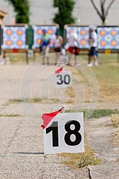 Olympic archery training fieldwith archery target and archers in the background and distance signs.
