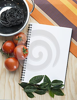 Kitchen note book on a tablecloth with tomatoes a bowl photo