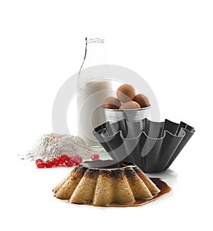 Front still life consisting of a bottle of milk, flour, egg yolk, eggs in a bowl, curled mold and a flan in the foreground