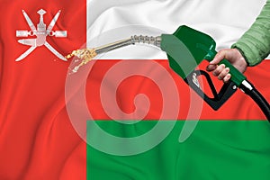 OMAN flag Close-up shot on waving background texture with Fuel pump nozzle in hand. The concept of design solutions. 3d rendering