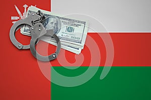 Oman flag with handcuffs and a bundle of dollars. The concept of breaking the law and thieves crimes
