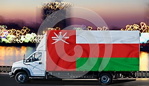 Oman flag on the side of a white van against the backdrop of a blurred city and river. Logistics concept